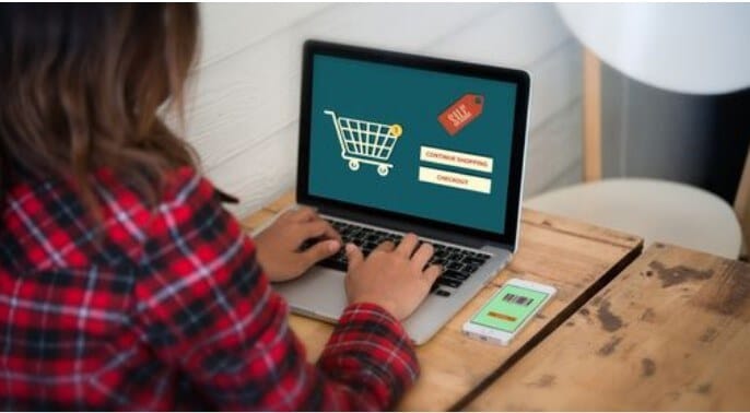 A lady wearing a red checked shirt blogging on her laptop blogger